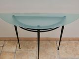 a glass table with a metal base and a glass bowl on it