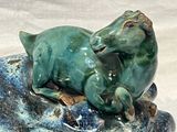 a statue of a horse that is laying down on a rock