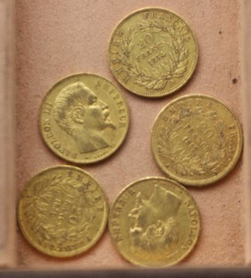 six types différents de pièces d'or dans une boîte posée sur une table