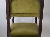 an old wooden chair with a green upholstered seat