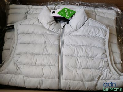 un gilet blanc posé dans une boîte sur laquelle est accrochée une étiquette