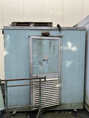 a blue refrigerator sitting outside of a building next to a wall