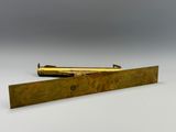 une paire de stylos plaqués laiton et une règle posés sur une surface blanche