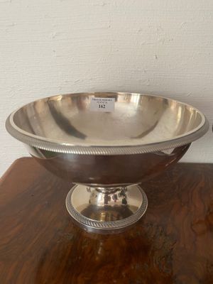 a silver bowl on a wooden table with a white wall in the background