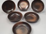 six bols marron sont disposés en cercle sur une surface blanche