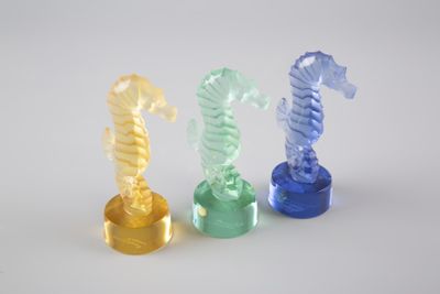 trois figurines d'hippocampes en plastique posées sur une surface blanche
