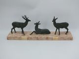three bronze deer statues on a marble base on a white background