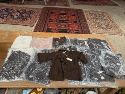 une table sur laquelle sont posés de nombreux vêtements, dans le salon