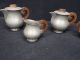 three silver teapots with wooden handles on a black background