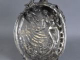 une assiette ancienne en argent sur laquelle est représentée une femme en robe