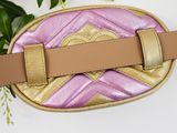 pink and gold belt bag with a gold buckle on a white surface
