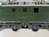 a green train that is sitting on the tracks