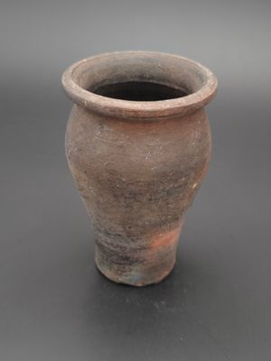 un vase brun posé sur une table à fond gris