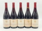 quatre bouteilles de vin sont alignées sur une surface blanche