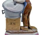 figurine of a man washing a pot on a wooden stand