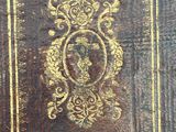 an old leather book with a gold design on the cover