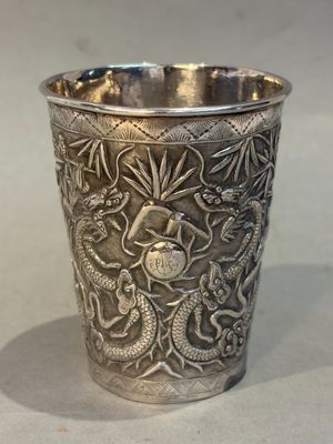 a silver cup with a dragon design on it