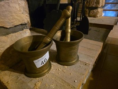 deux mortiers posés sur une table en pierre près d'une cheminée