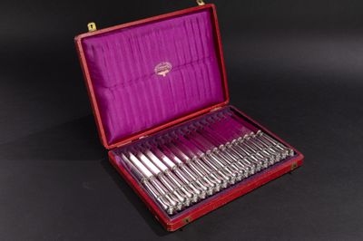 un coffret rouge contenant de l'argenterie, posé sur une surface noire