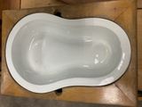 a white bath tub sitting on top of a wooden table