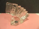 a clear glass vase with a glass holder on a pink surface