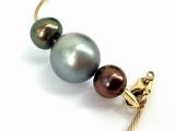 two black and brown pearls on a gold chain on a white background