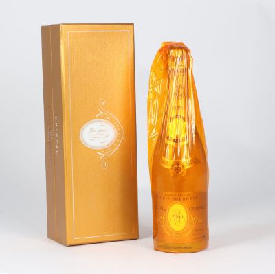 an orange bottle of perfume next to a gold box on a white surface
