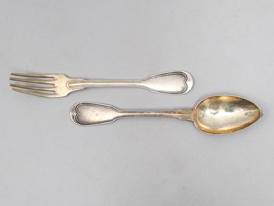 deux cuillères et une fourchette en argent sur une surface blanche