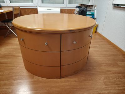 une photo d'une table ronde avec des tiroirs dans une pièce