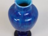 a small blue vase sitting on a white surface