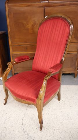 Fauteuil Voltaire garnie de tissu rouge. État d’usage