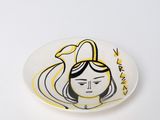 une assiette blanche sur laquelle est dessiné le visage d'une femme