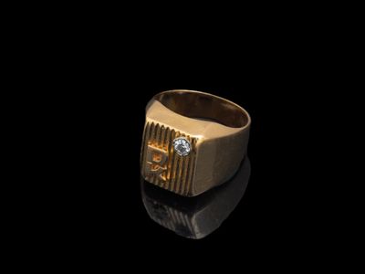 un gros plan d'une bague en or sertie d'un diamant sur un fond noir