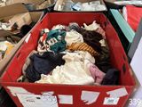 a red box filled with lots of clothes on the floor