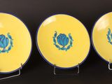 three yellow plates with blue designs on them sitting on a table