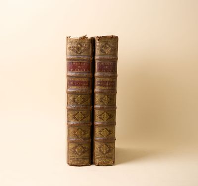 deux vieux livres posés l'un sur l'autre sur une surface blanche