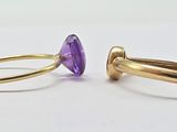 two gold rings with amethorate stones on them on a white surface