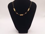 a black mannequin with a gold necklace on it