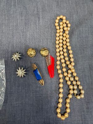 un collier, des boucles d'oreilles et des bracelets en perles dorées disposés sur une surface grise