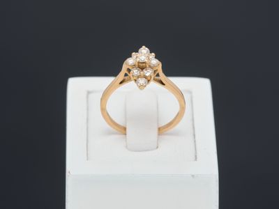 une bague en or jaune sertie de trois diamants, posée sur un écrin blanc