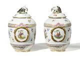 pair of vases with a bird on top of them on a white surface