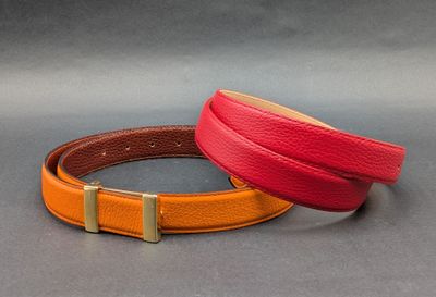deux bracelets en cuir de couleurs différentes posés sur une surface grise