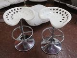 trois tabourets blancs posés sur un parquet, à côté d'un canapé blanc