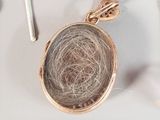 a gold locke with a hair ball inside of it