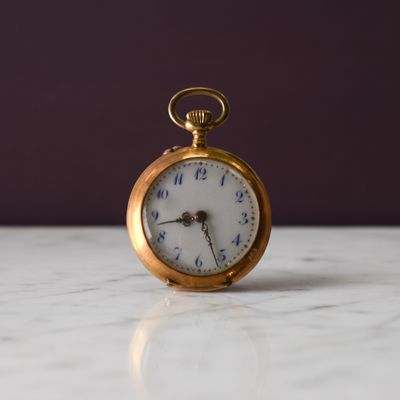 une montre de poche en or posée sur une table en marbre