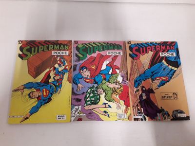 trois bandes dessinées de Superman posées sur une surface blanche