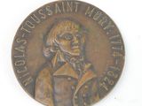 a bronze medal with a portrait of a man on it