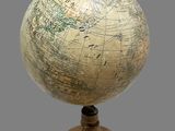 a small globe on a wooden stand with a gray background