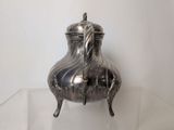 a silver tea pot on a clear glass table