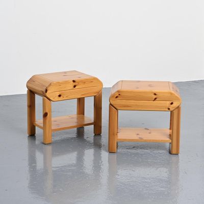 deux petits tabourets en bois placés l'un à côté de l'autre sur un sol en béton